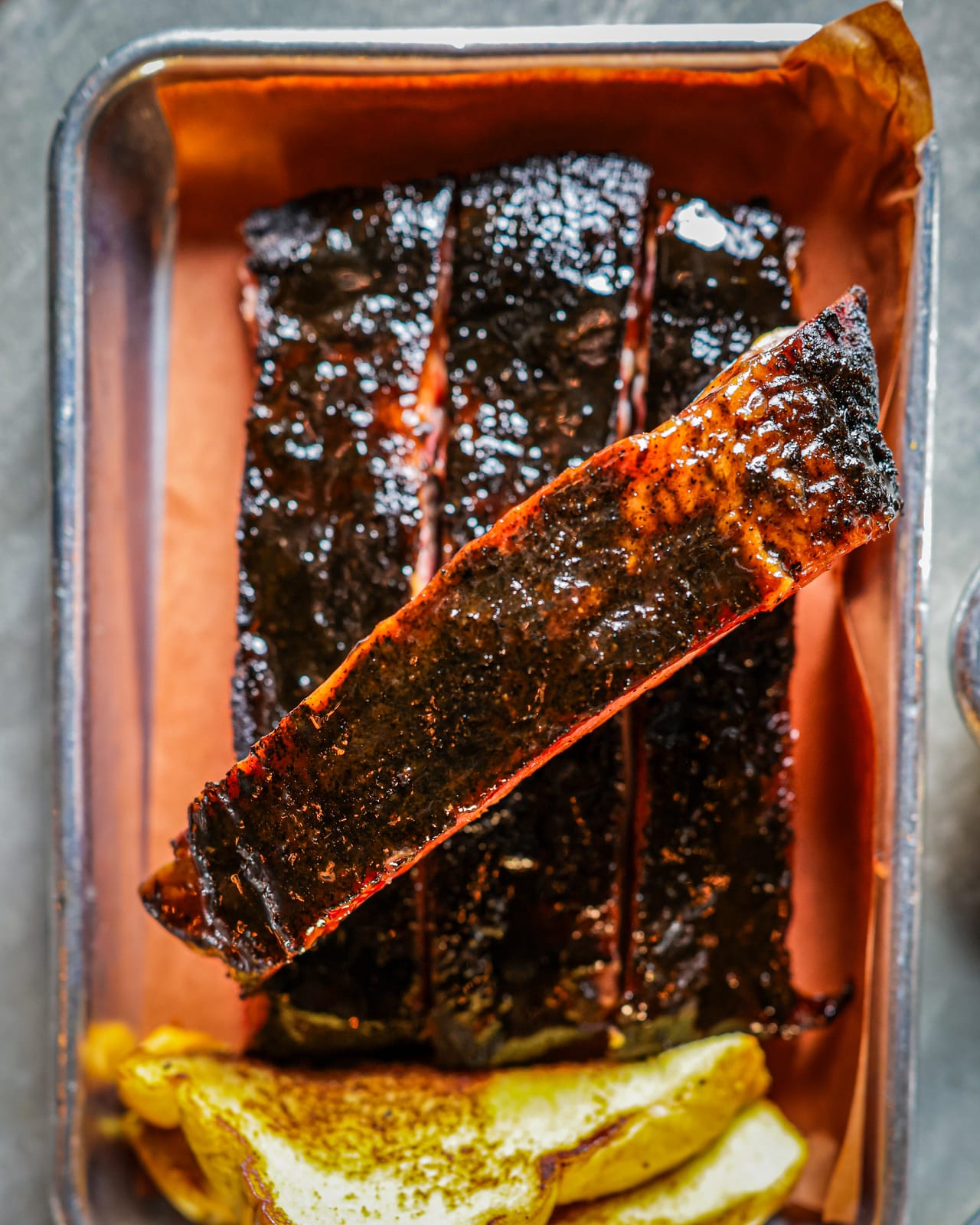 Cafecito-rubbed Cheshire spare ribs lacquered in oro negro sauce with maduros at Apocalypse BBQ Kendall